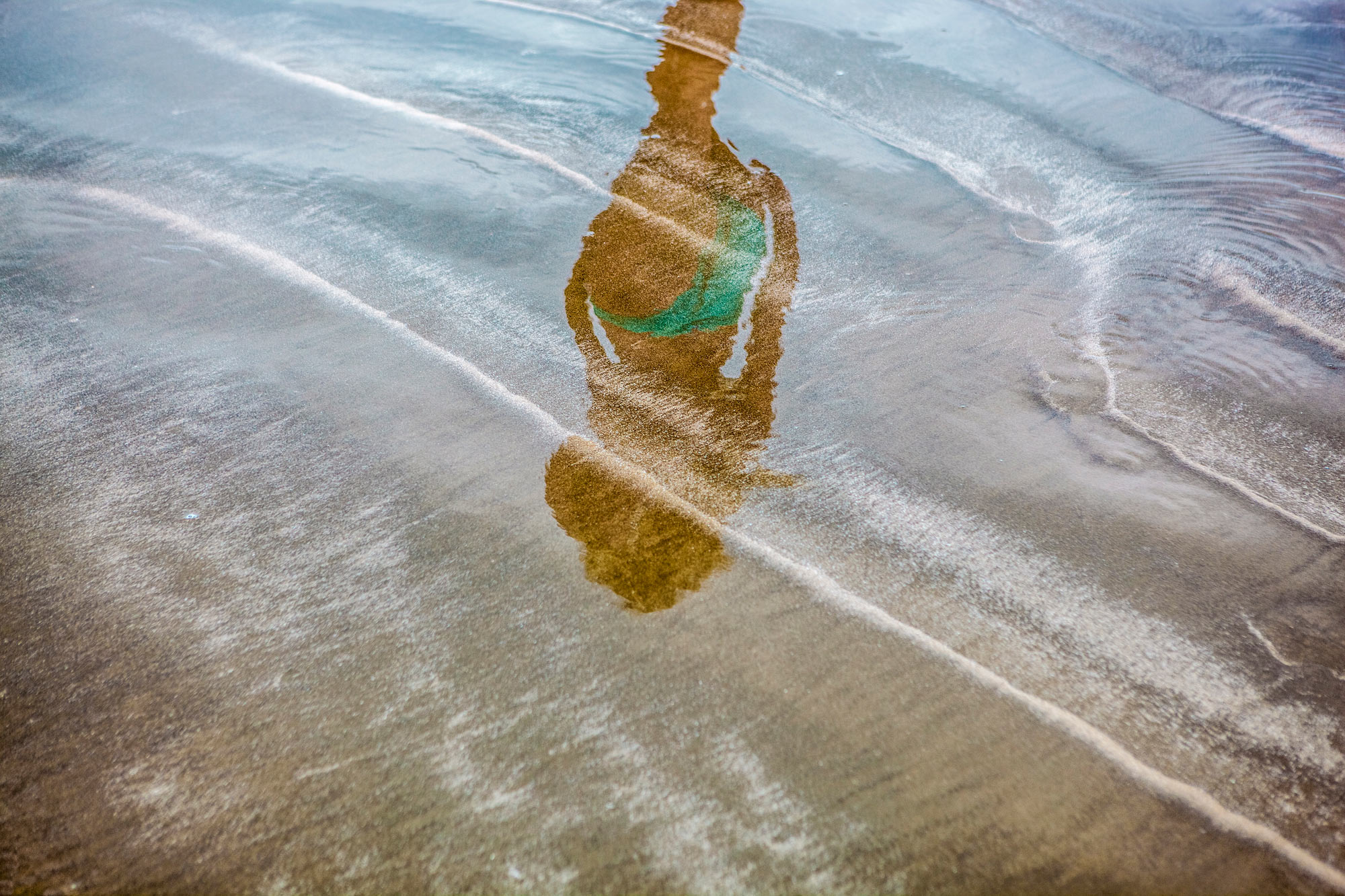 Girl reflected in sand on Texas beach