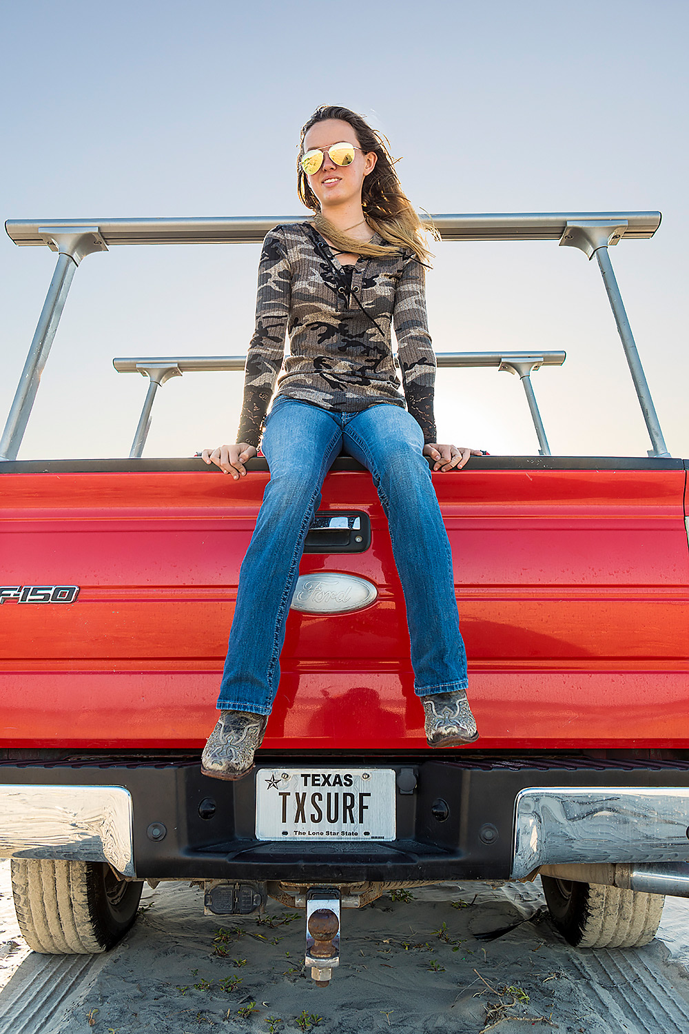Texas surfer girl on tailgate of red Ford truck