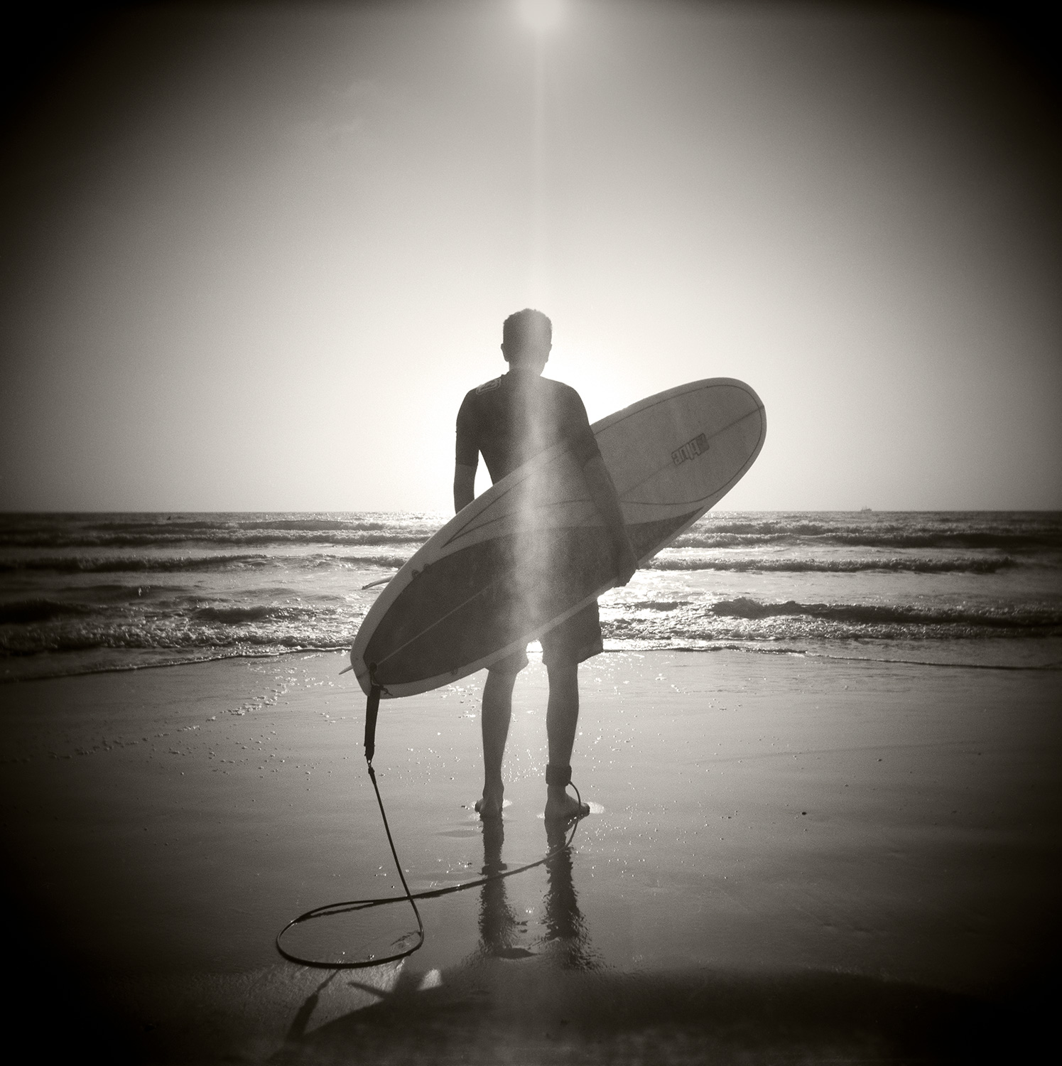 Lone Surfer holding surfboard
